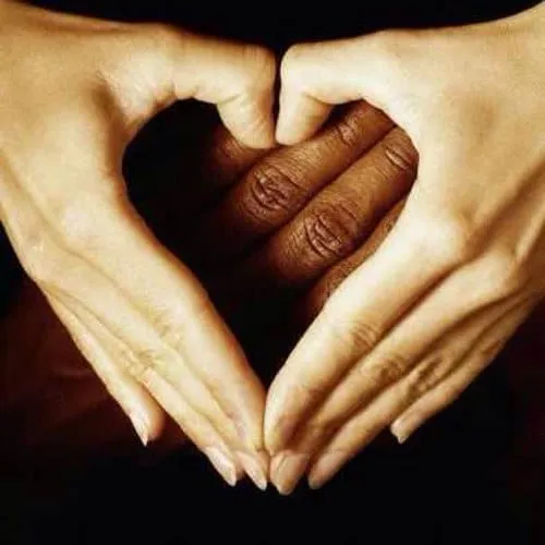 Image shared for the series Destined to Be: two pale hands forming a heart around a third, darker hand against a black background