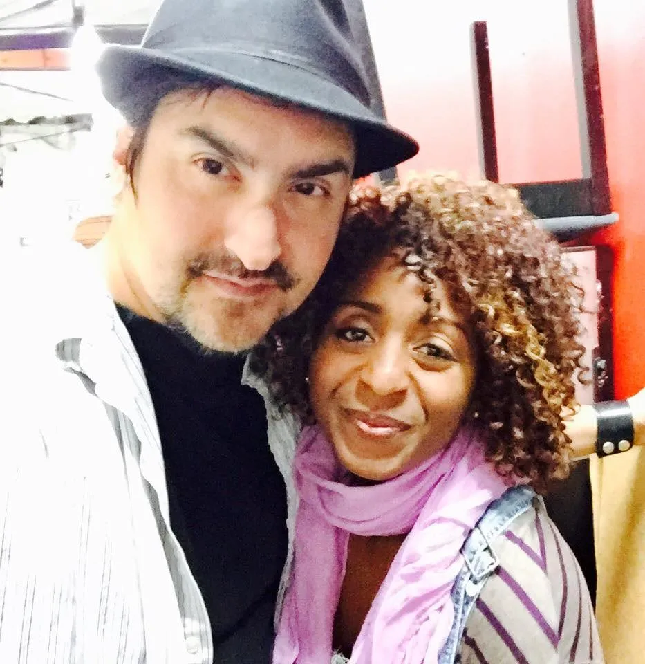 Close selfie at a Brightside screening of a bearded man in a dark fedora beside a smiling woman with curly hair and a lilac scarf.