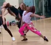 Sophia Thomas in hot pink pants mid-move among other dancers in a mirrored studio, a still from a 30-second dance combination.