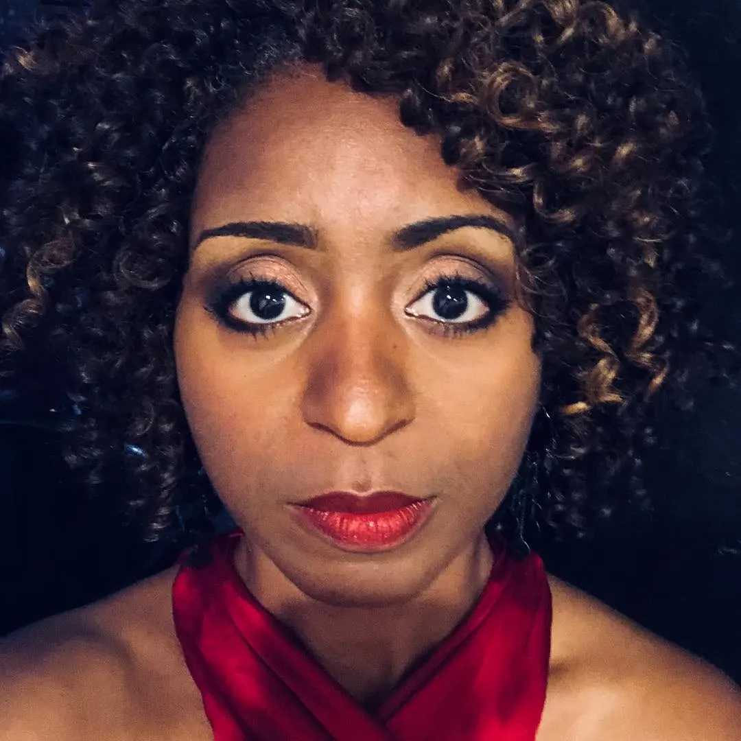 Sophia Thomas as Jasmine Jeffers in a close-up wrap photo from the It’s a Date shoot, in a red halter top and red lipstick.