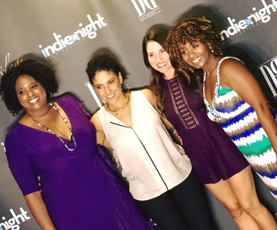 Four smiling women from the Just Jackie cast pose in front of the Indie Night Film Festival backdrop on the red carpet in Hollywood