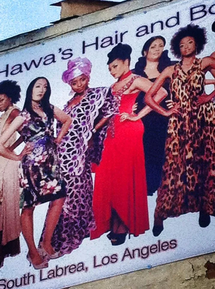 Close-up of the Hawa’s Hair and Boutique billboard on South La Brea, with models in colorful gowns including Sophia Thomas in lavender African attire