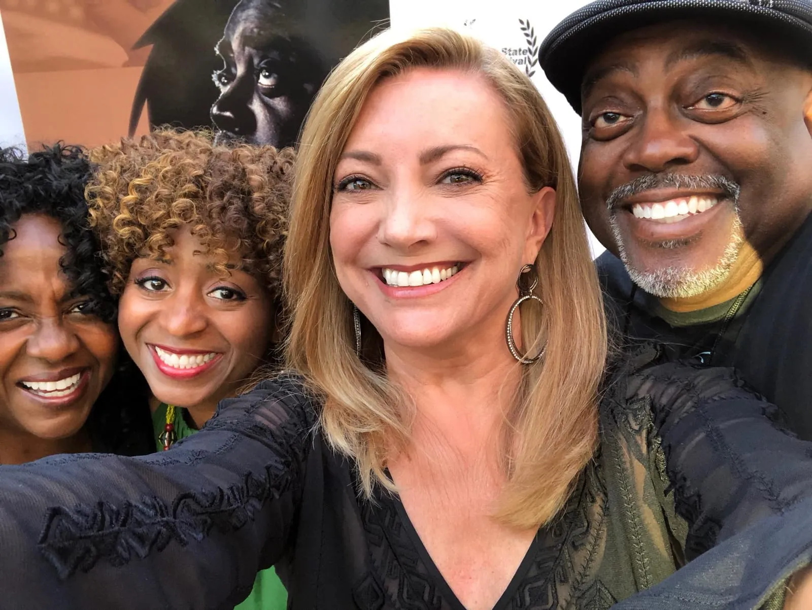 Group selfie of four smiling people in front of the My Name Is Lamar poster at the Golden State Film Festival.