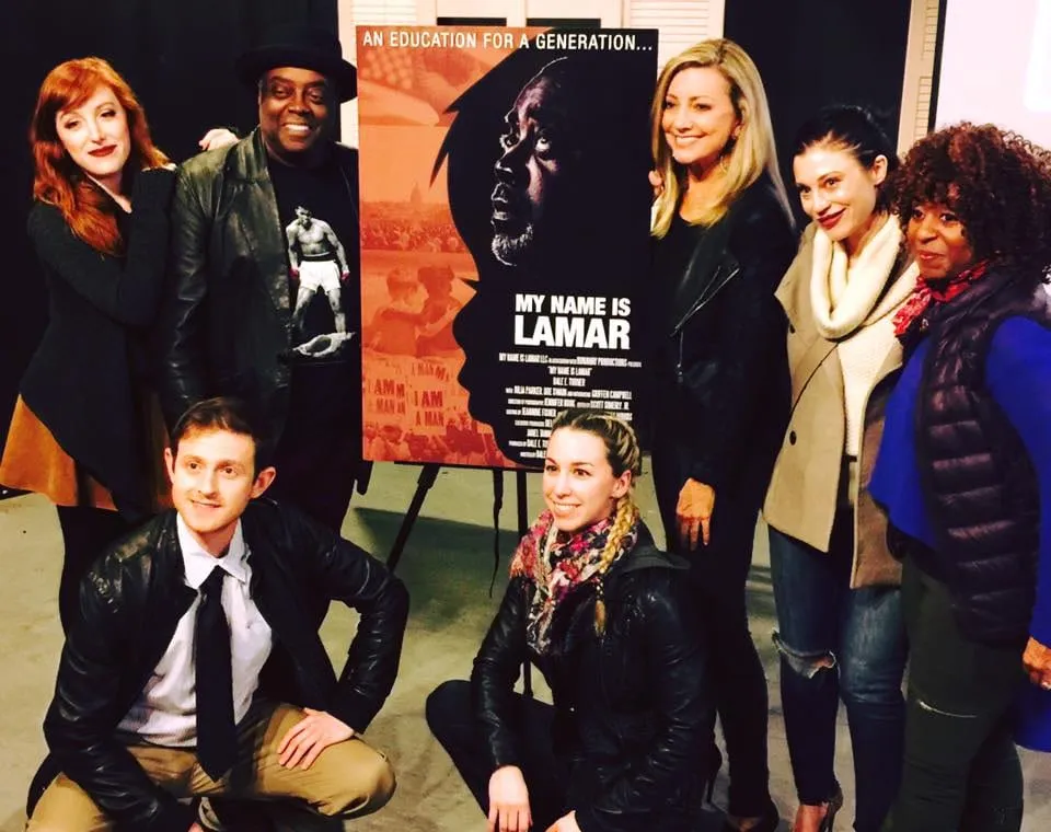 Seven cast and crew members of My Name Is Lamar pose around the film’s poster at the cast and crew screening at The Secret Rose Theater