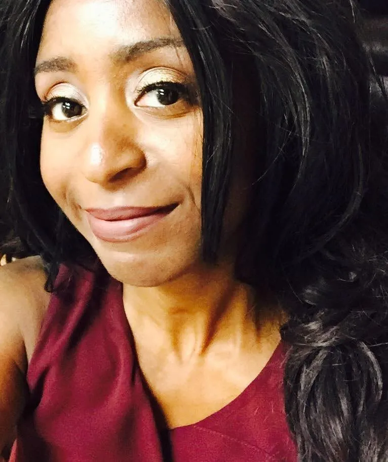 Close-up selfie of a smiling woman with long black wavy hair and a burgundy top, from the Review Rage shoot
