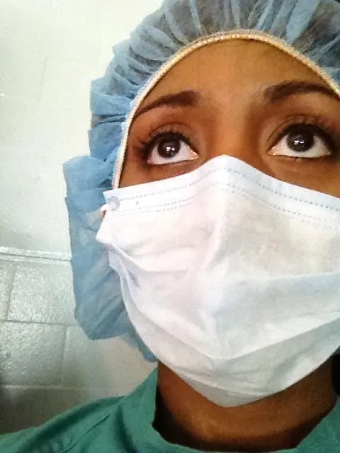Close-up of a person in a blue surgical cap, white face mask and green scrubs looking upward, a nurse look tied to the film Vicious.